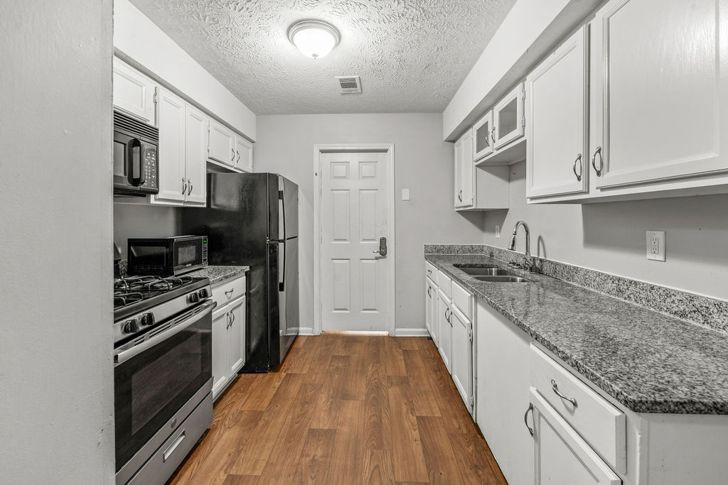 Galley kitchen with granite counters and black appliances